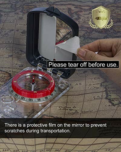 Hand peeling protective film from compass mirror on map.