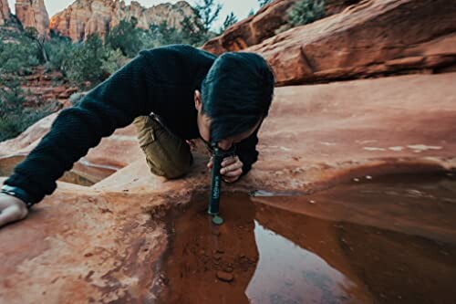 Person examining water with a tool in a desert landscape